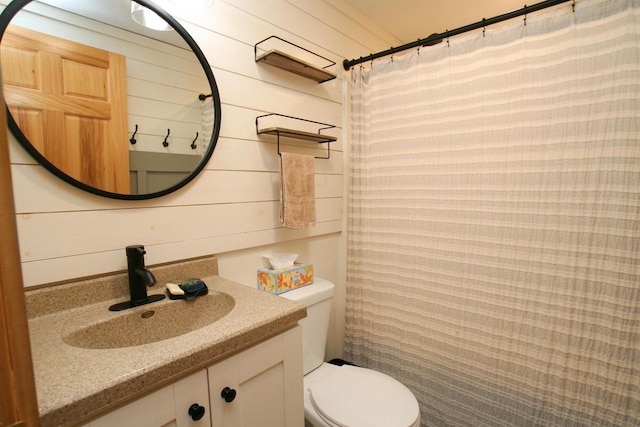 full bath featuring vanity, toilet, and wood walls