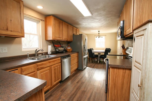 kitchen featuring dark countertops, stainless steel appliances, dark wood-type flooring, and a sink