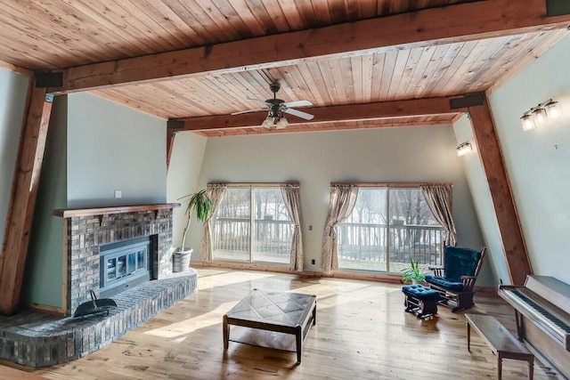 living area with ceiling fan, beam ceiling, wood finished floors, and a fireplace