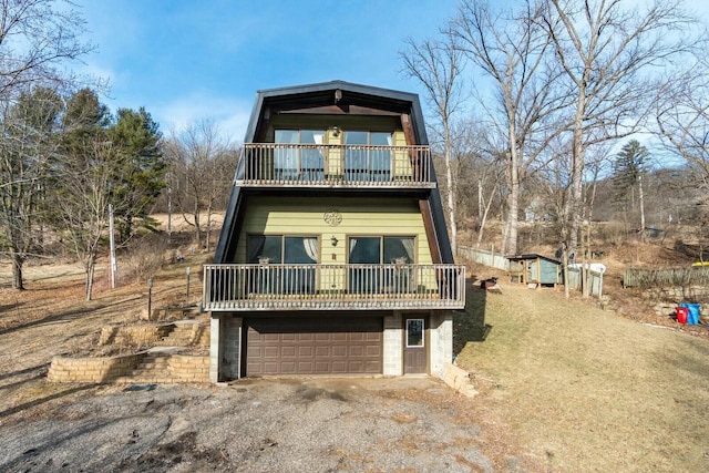 a-frame home featuring a balcony, an attached garage, and driveway