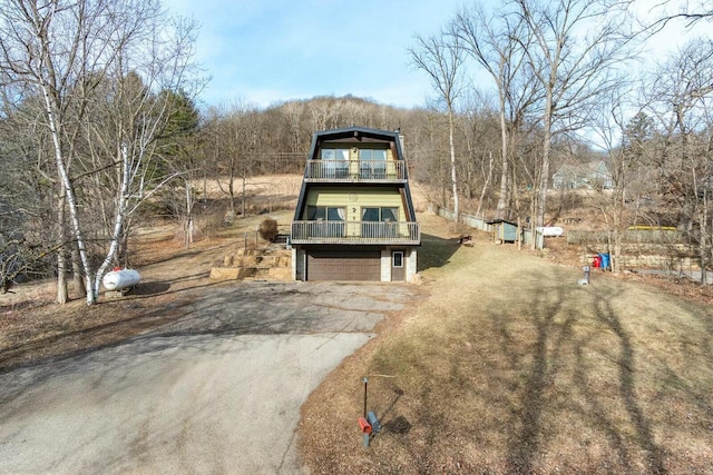 view of front of property featuring aphalt driveway, a balcony, and an attached garage