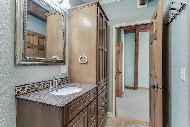 bathroom featuring vanity, a textured wall, and baseboards