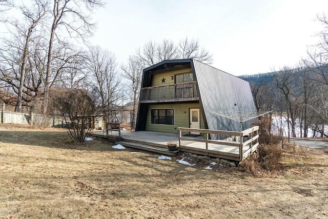 rear view of house with a deck, a balcony, fence, and a gambrel roof