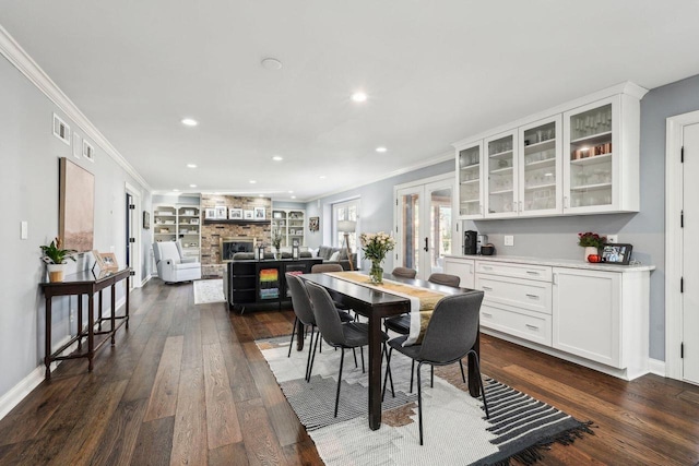 dining space with dark wood-style floors, recessed lighting, a large fireplace, and ornamental molding