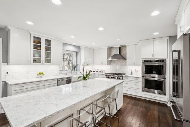 kitchen with white cabinets, wall chimney exhaust hood, and appliances with stainless steel finishes