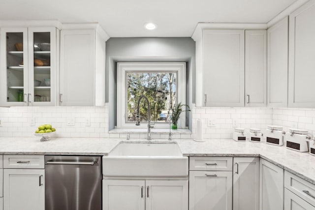 kitchen with a sink, backsplash, glass insert cabinets, white cabinets, and stainless steel dishwasher