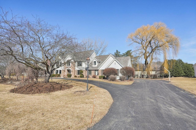 view of front of house featuring aphalt driveway, stone siding, and a front yard