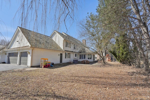 view of front facade with driveway, a chimney, and a garage