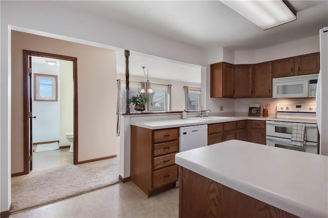 kitchen featuring light carpet, a sink, white appliances, a peninsula, and light countertops