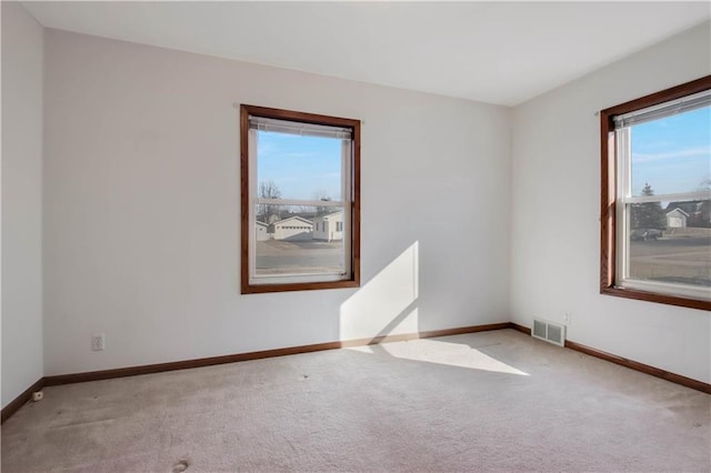 carpeted spare room with visible vents and baseboards