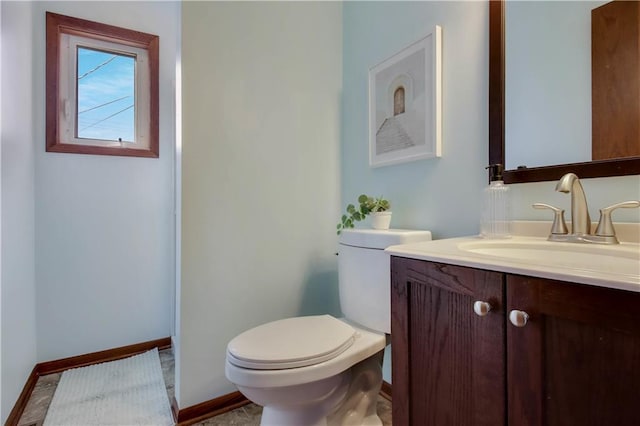 half bath featuring toilet, vanity, and baseboards