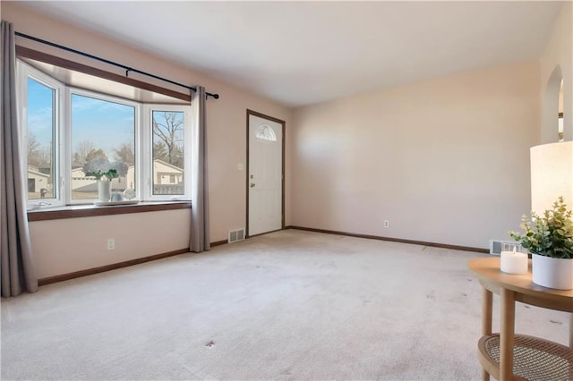 interior space with baseboards, visible vents, and light carpet