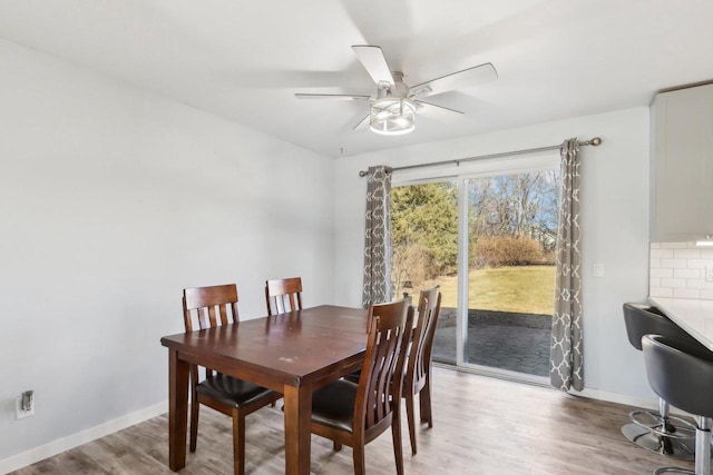 dining area featuring a ceiling fan, baseboards, and light wood finished floors