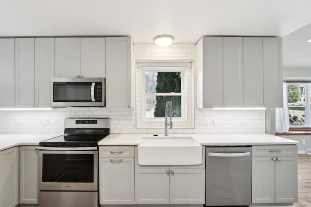 kitchen with light countertops, backsplash, appliances with stainless steel finishes, and a sink