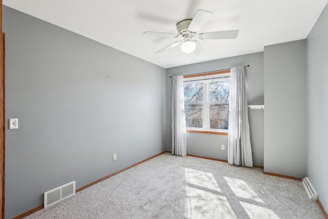 spare room featuring carpet, baseboards, visible vents, a baseboard radiator, and ceiling fan