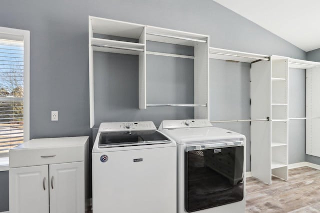 laundry area with baseboards, cabinet space, light wood-style floors, and washing machine and clothes dryer