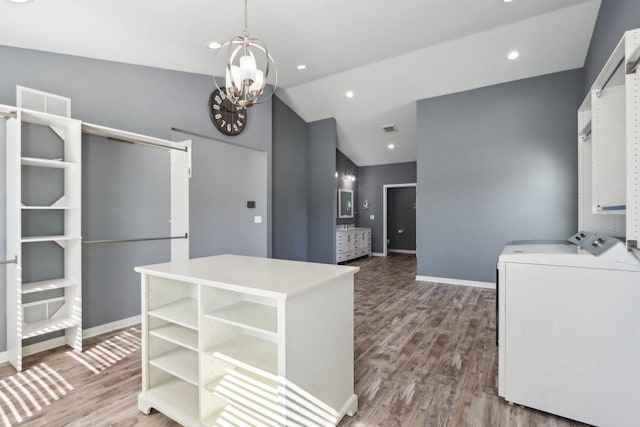 kitchen featuring washer and clothes dryer, visible vents, lofted ceiling, and wood finished floors