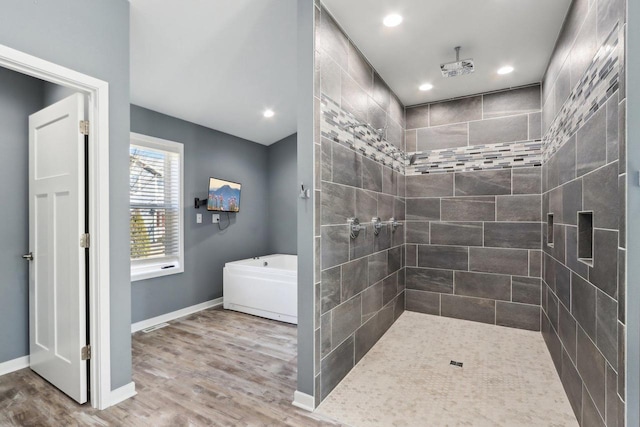 full bath featuring wood finished floors, a tile shower, recessed lighting, baseboards, and a bath