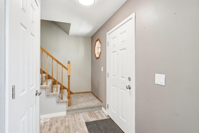 entrance foyer featuring visible vents, stairway, light wood-style floors, and baseboards