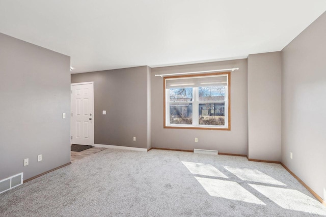 unfurnished room with visible vents, light carpet, and baseboards