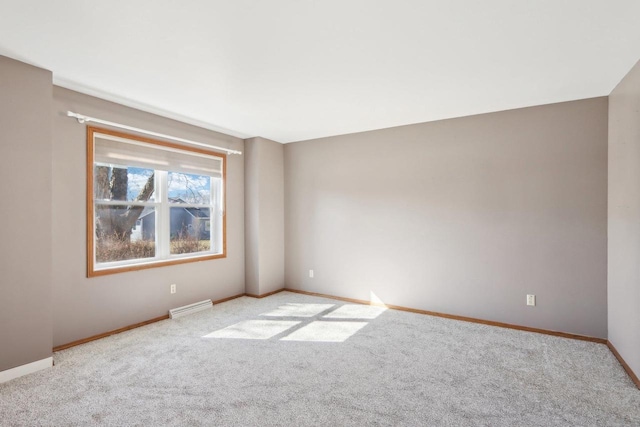 spare room with carpet flooring, baseboards, and visible vents