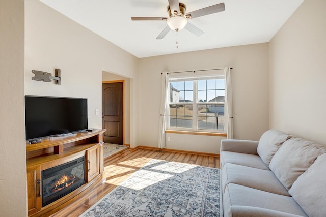 living room with baseboards, light wood-style floors, and ceiling fan