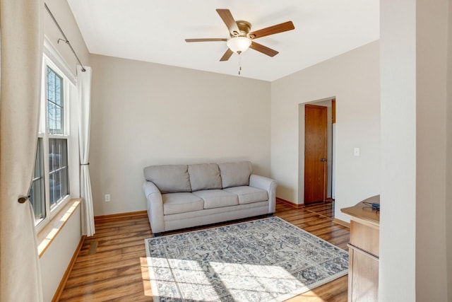 living area with baseboards, ceiling fan, and light wood finished floors