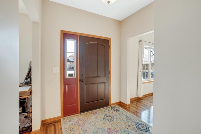 foyer entrance featuring visible vents, baseboards, and wood finished floors