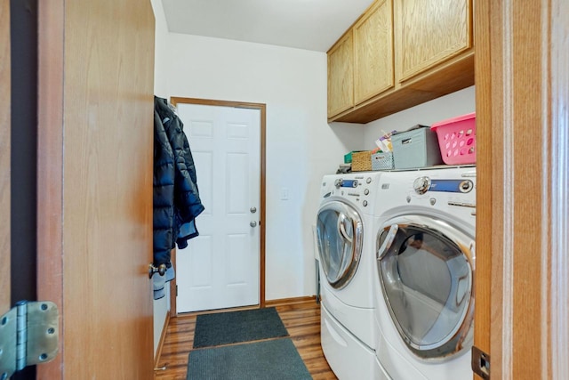 laundry room with wood finished floors, cabinet space, baseboards, and washing machine and clothes dryer