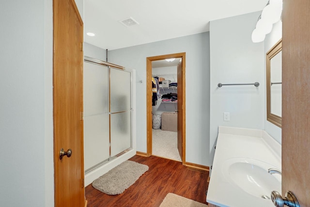 bathroom with vanity, wood finished floors, visible vents, a stall shower, and a walk in closet