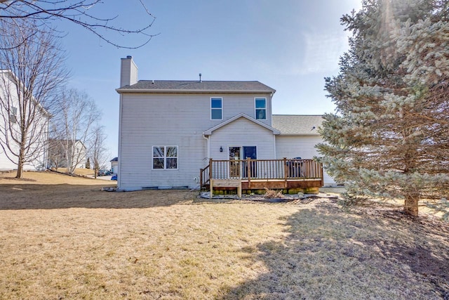 back of property featuring a wooden deck, a lawn, and a chimney