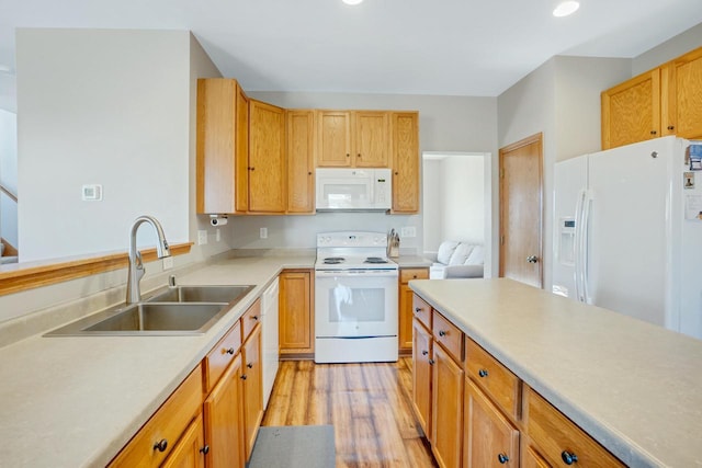 kitchen with light countertops, light wood-type flooring, recessed lighting, white appliances, and a sink