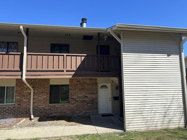 view of front of home with brick siding and a balcony