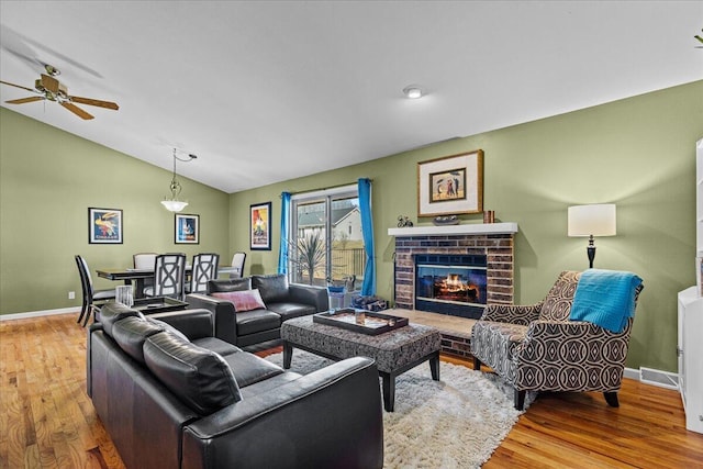 living room featuring visible vents, a fireplace, lofted ceiling, and wood finished floors