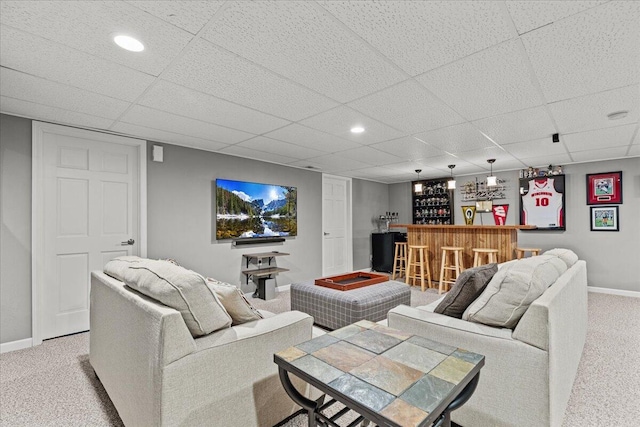 living area featuring a drop ceiling, recessed lighting, baseboards, light colored carpet, and a dry bar