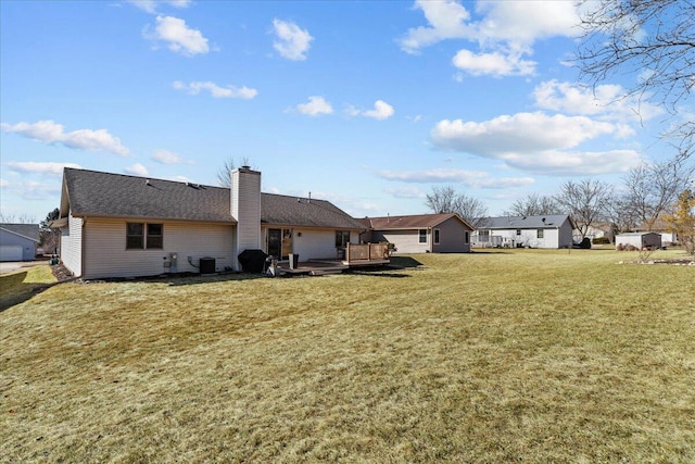 rear view of house with a wooden deck, a yard, cooling unit, and a chimney