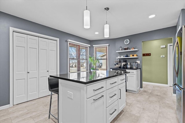 kitchen featuring dark countertops, a kitchen bar, freestanding refrigerator, white cabinetry, and open shelves