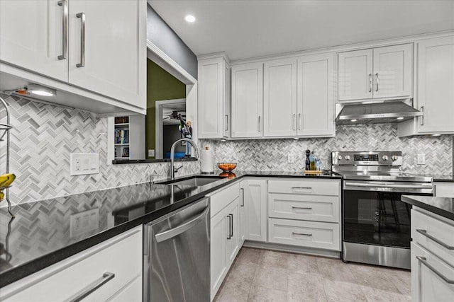 kitchen featuring dark countertops, under cabinet range hood, appliances with stainless steel finishes, white cabinetry, and a sink