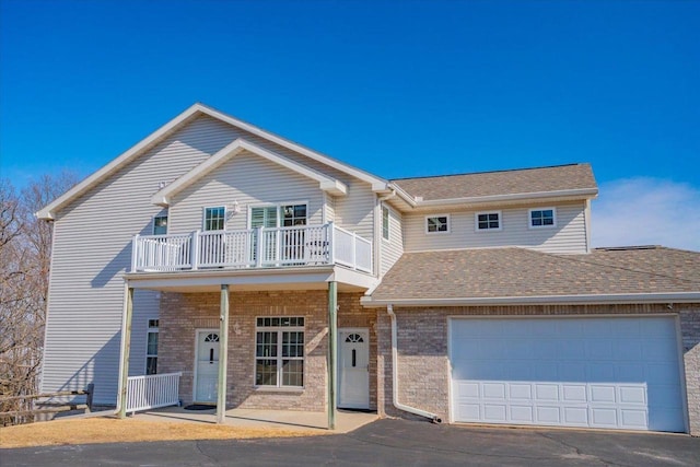 view of front of home with brick siding, roof with shingles, and a balcony