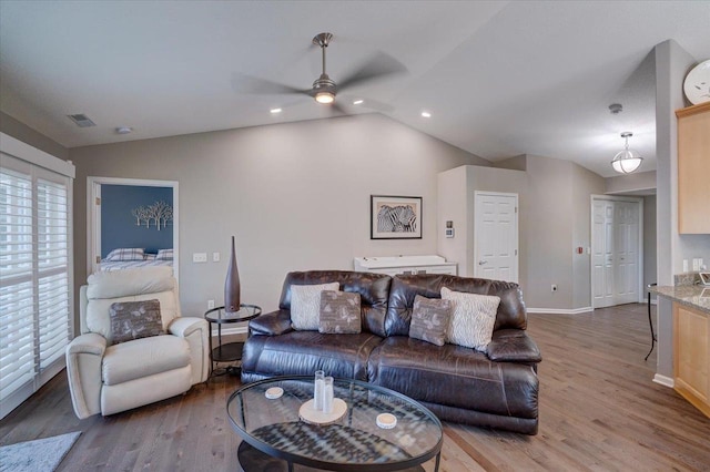 living room featuring vaulted ceiling, wood finished floors, visible vents, and baseboards