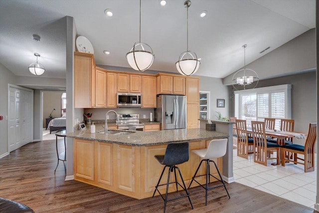 kitchen featuring a breakfast bar area, light stone countertops, appliances with stainless steel finishes, and a peninsula