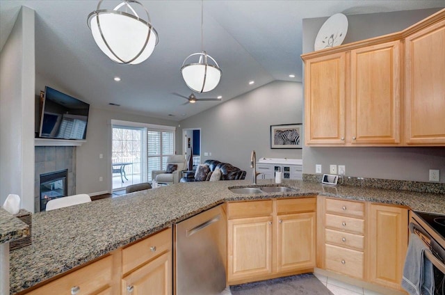 kitchen featuring light brown cabinets, a tile fireplace, appliances with stainless steel finishes, and a sink