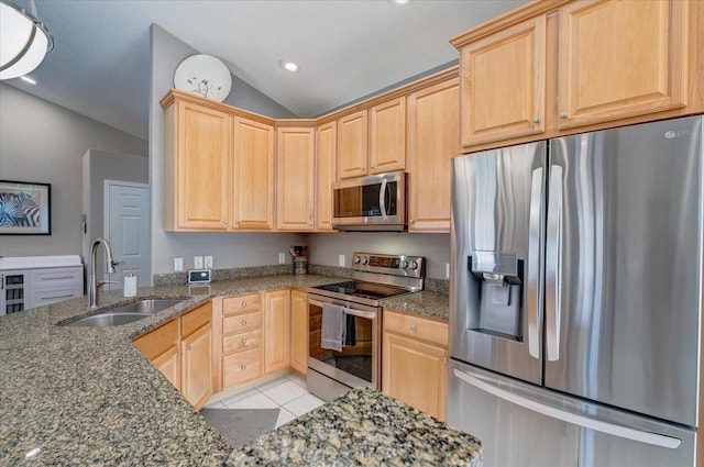 kitchen featuring light brown cabinetry, a sink, stainless steel appliances, light tile patterned floors, and vaulted ceiling