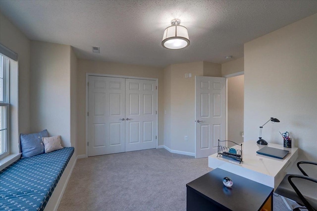 office space featuring visible vents, light colored carpet, baseboards, and a textured ceiling