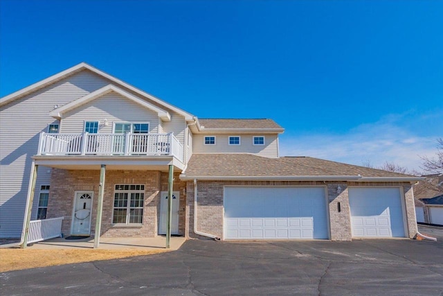 view of front of property featuring aphalt driveway, an attached garage, brick siding, and a shingled roof