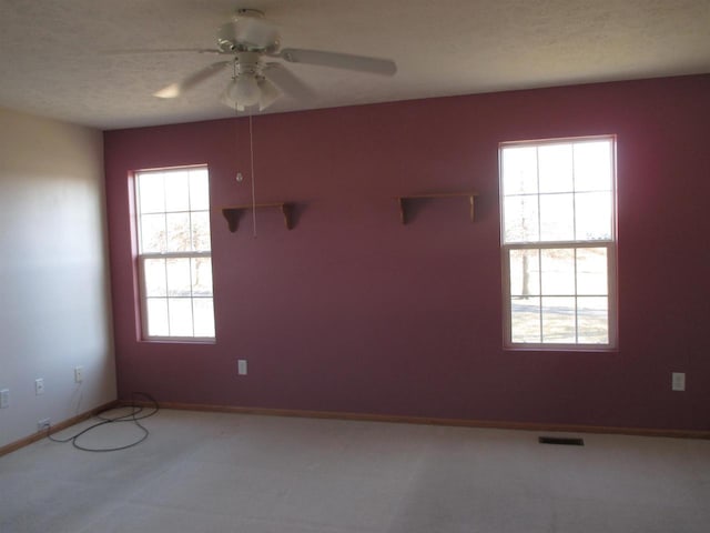 unfurnished room with visible vents, baseboards, a textured ceiling, and a ceiling fan