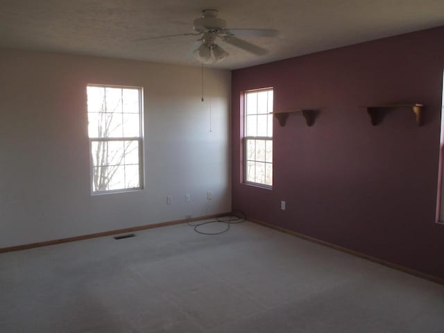 unfurnished room with a ceiling fan, carpet, baseboards, and visible vents