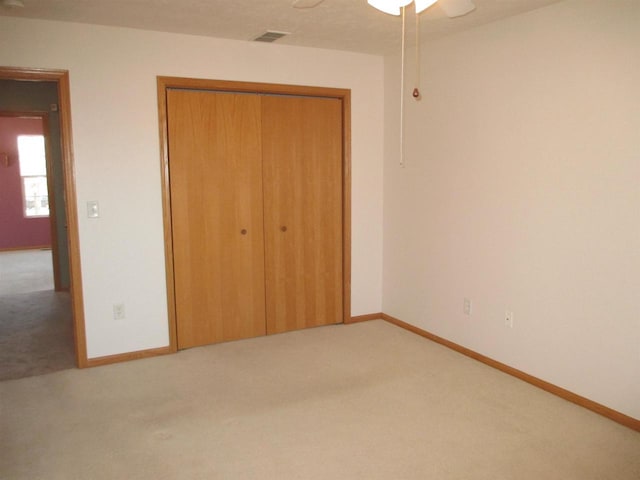 unfurnished bedroom featuring a ceiling fan, carpet, a closet, and baseboards