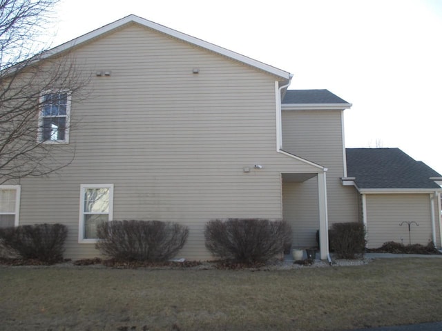 view of side of property featuring a yard and roof with shingles