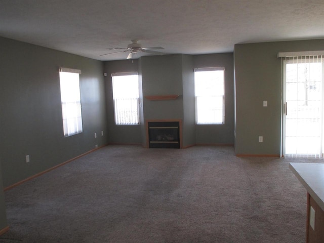 unfurnished living room featuring carpet, a fireplace, baseboards, and a ceiling fan